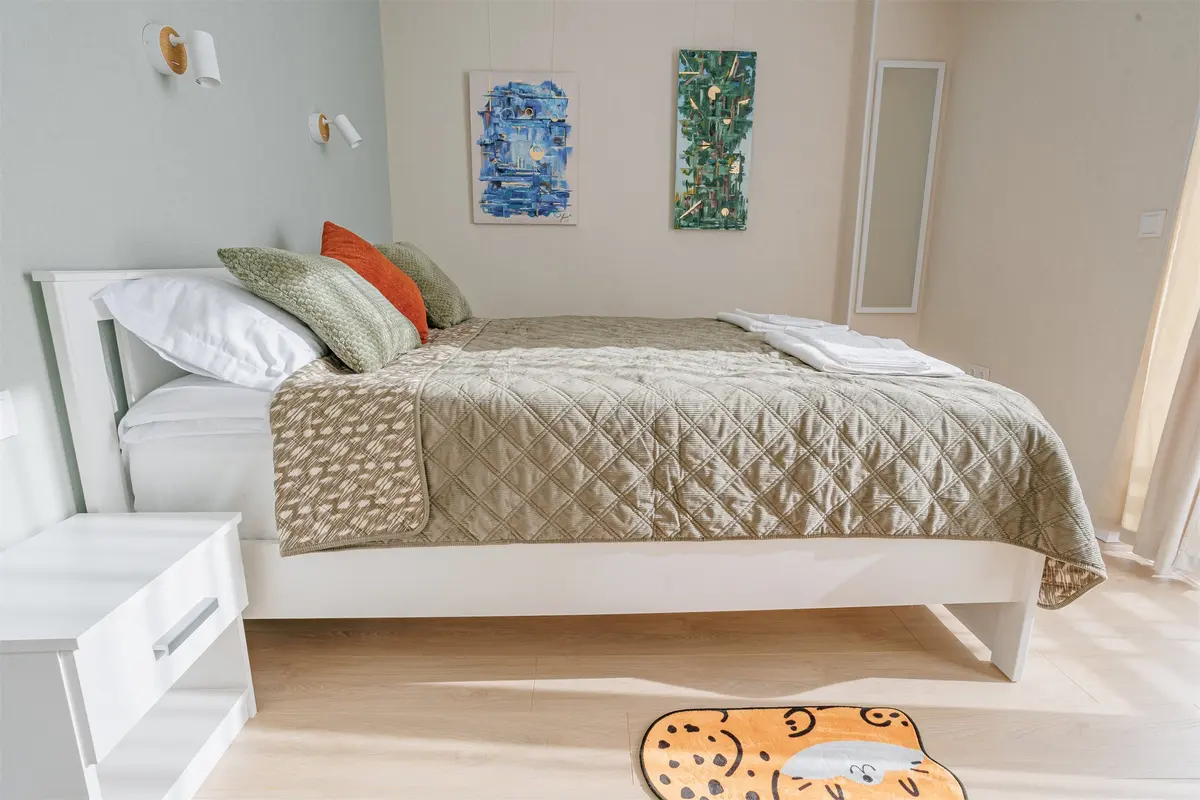 Separate bedroom with prepared bed, original artwork and closing door